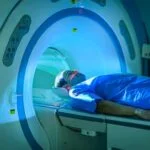 A man wearing blue robes moving into MRI machine