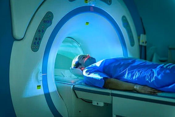 A man wearing blue robes moving into MRI machine